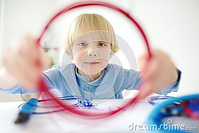 Little boy learning make model with 3d printing pen. Child playing with new modern toy for creativity. DIY. STEM and STEAM Stock Photo