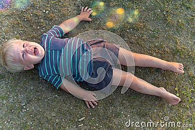 A little boy lies on the ground and cries a lot. resentment or hysteria in a child Stock Photo