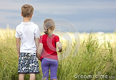 Little boy and little girl standing holding hands looking on horizont Stock Photo