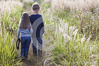 Little boy and little girl standing holding hands looking on horizont. Rear view. Stock Photo