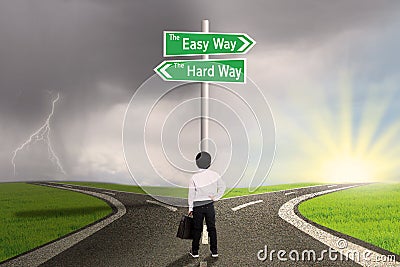 Little boy looking at sign of easy vs hard way Stock Photo