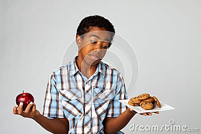 Little boy making decisions of eating healthy verses unhealthy. Stock Photo