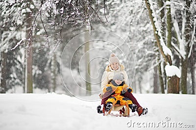 Little boy and mother/grandmother/nanny sliding in the Park during a snowfall Stock Photo