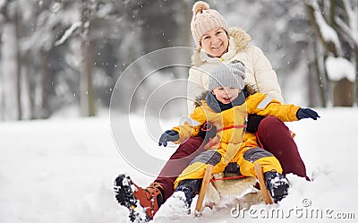 Little boy and mother/grandmother/nanny sliding in the Park during a snowfall Stock Photo