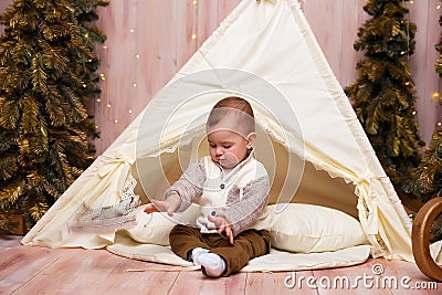 A little boy near the tent, tipi, wigma and christmas trees, is playing Stock Photo
