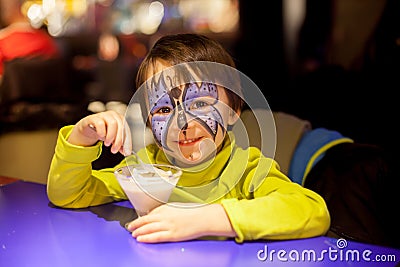 Little boy with painted face as butterfly, eating ice cream Stock Photo