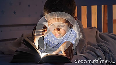 Little boy in pajamas being awake at night reading books with flashlight. Children education, development, secrecy, privacy, Stock Photo