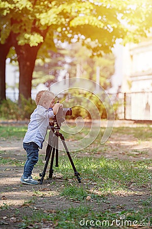 Little boy photographing on the camera on tripod in the park Stock Photo