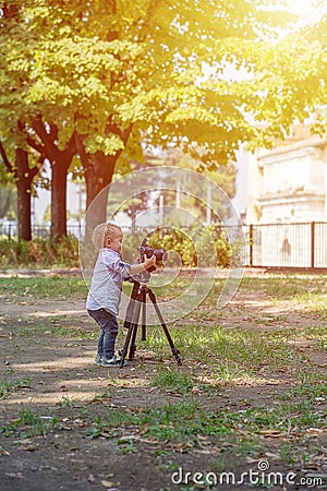 Little boy photographing on the camera on tripod in the park Stock Photo