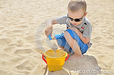 Little boy playing on the beach in the sand. Child sculpts figures out of the sand. Activities in the summer on the sea Stock Photo