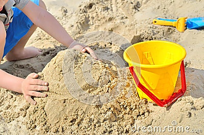 Little boy playing on the beach in the sand. Child sculpts figures out of the sand. Stock Photo