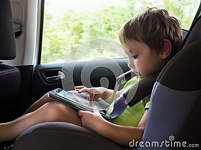 Little boy playing on computer tablet in the car Stock Photo