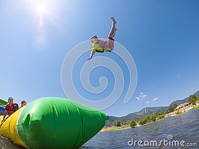 Little boy playing on inflatable water toy at the lake Stock Photo