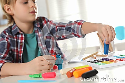 Little boy playing with plasticine at table, closeup. Creative hobby Stock Photo