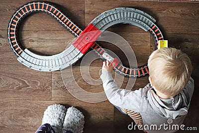 A little boy plays a children`s railway. Mom is watching her son from above. The child is fascinated by the train Stock Photo