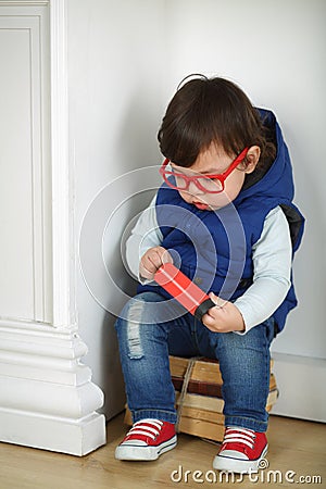 Little boy in red with glasses sitting on a bunch Stock Photo