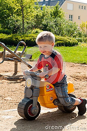 Little boy ridding his yellow toy motorcycle Stock Photo