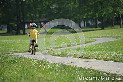 Little boy riding his bicycle on a twisting narrow road Stock Photo