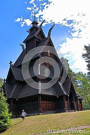 Little boy running and playing in front of the Gol Church, a stave church originally built in Gol city, now in Oslo. Stock Photo