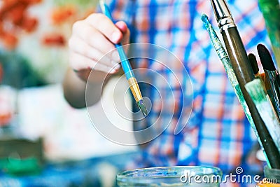 Little boy`s hand holding paintbrush. Concept of early childhood education, painting, talent. Stock Photo