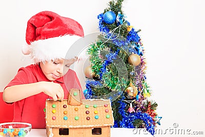 Little boy in Santa's hat building gingerbread Stock Photo