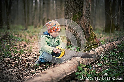 Little boy sawing a fallen tree in the forest Stock Photo