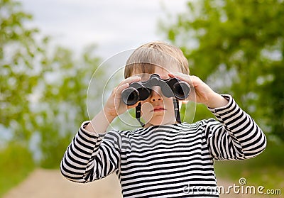 Little boy scanning the woods with binoculars Stock Photo
