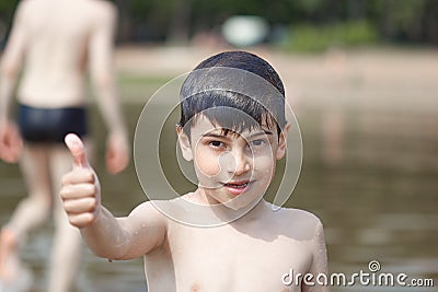 A little boy shows a thumbs up like in the middle of frozen water droplets in the air Stock Photo