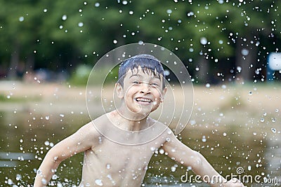 A little boy shows a thumbs up like in the middle of frozen water droplets in the air Stock Photo