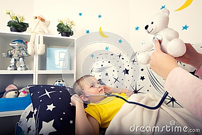 A child listens to a toy bear with a phonendoscope. Stock Photo