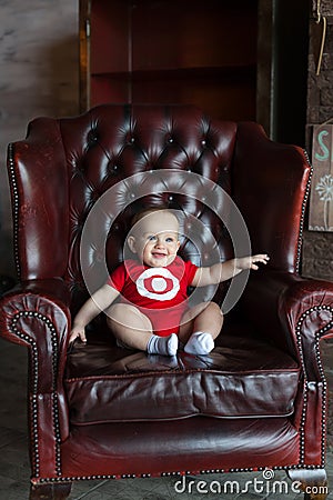 A little boy sits in a leather chair. Happy family life. Man was born Stock Photo