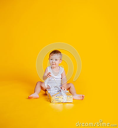 A little boy sits in a T-shirt and underpants next to a big gift box Stock Photo