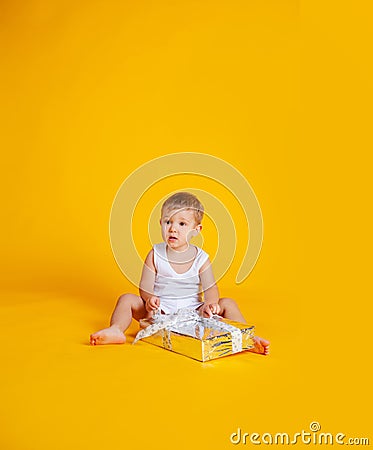 A little boy sits in a T-shirt and underpants next to a big gift box Stock Photo