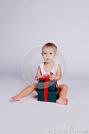 A little boy sits in a T-shirt and underpants next to a big gift box Stock Photo