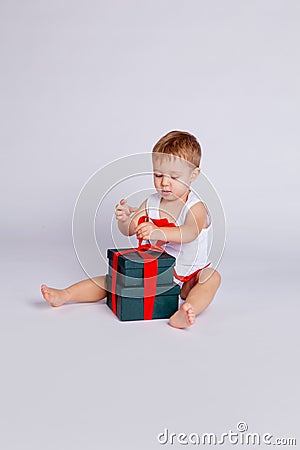 A little boy sits in a T-shirt and underpants next to a big gift box Stock Photo