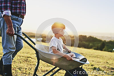 Boy sitting in wheelbarrows at sunset Stock Photo