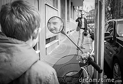 Little boy smiling at the scooter rear view mirror Stock Photo