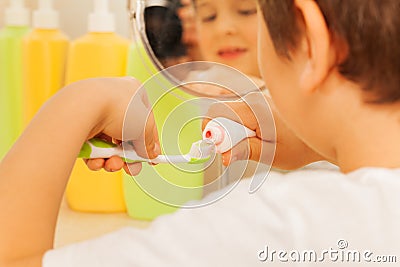 Little boy spreading toothpaste on a toothbrush Stock Photo