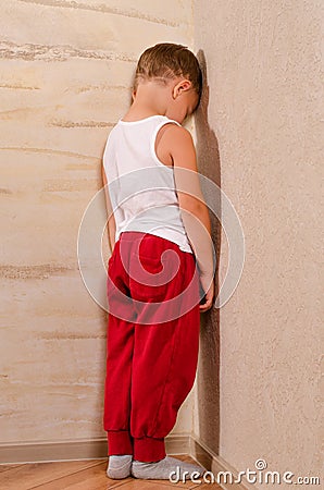 Little boy standing in a corner sulking Stock Photo