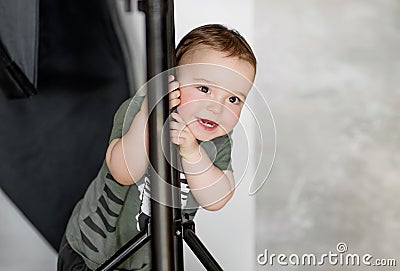 The little boy stands relying on the rack Stock Photo