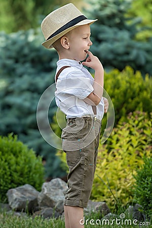 A little boy in a straw hat walks in the Park.Small ,shy boy Stock Photo