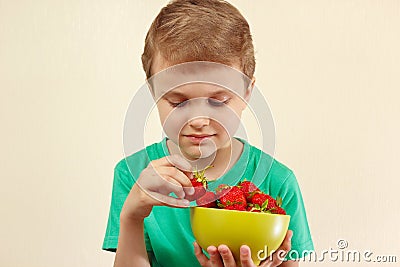 Little boy takes strawberry from the bowl Stock Photo