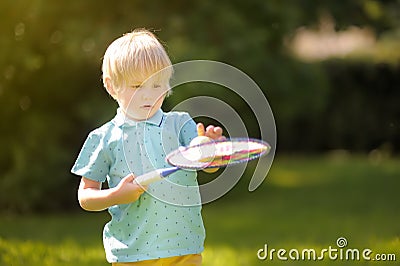 Little boy during tennis training or workout. Preschooler playing badminton in summer park. Child with small tennis racket and Stock Photo