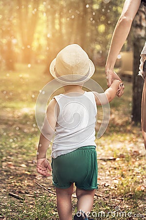 Little boy walking with mom in park. Stock Photo