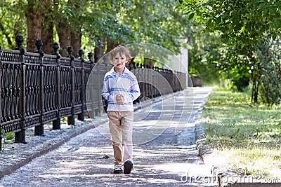 Little boy walking on a sunny street Stock Photo