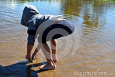 Little boy in water in lake. Child in clothes costs knee-deep in river Stock Photo