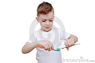 Little boy in white t-shirt squeezes toothpaste on brush. Health care, hygiene and childhood concept. Caries prevention Stock Photo
