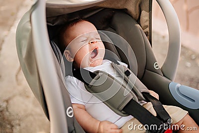 a little boy yawns strapped in a stroller. Stock Photo