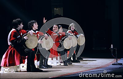 Little boys dressed in national costumes playing Georgian folk musical instrument doli on stage. Editorial Stock Photo