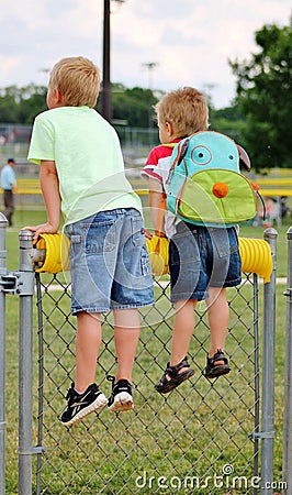Little boys on a fence looking onto a baseball field Editorial Stock Photo